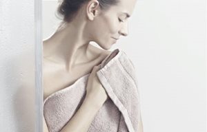 Femme épongeant sa peau après la douche.