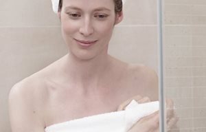 Femme après la douche, enveloppée dans une serviette, un turban en serviette sur la tête
