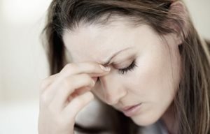 Femme stressée, le regard baissé - sa main touche son front