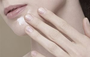 Femme appliquant de la crème sur son menton.
