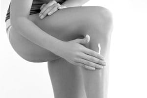 Femme touchant sa jambe gauche